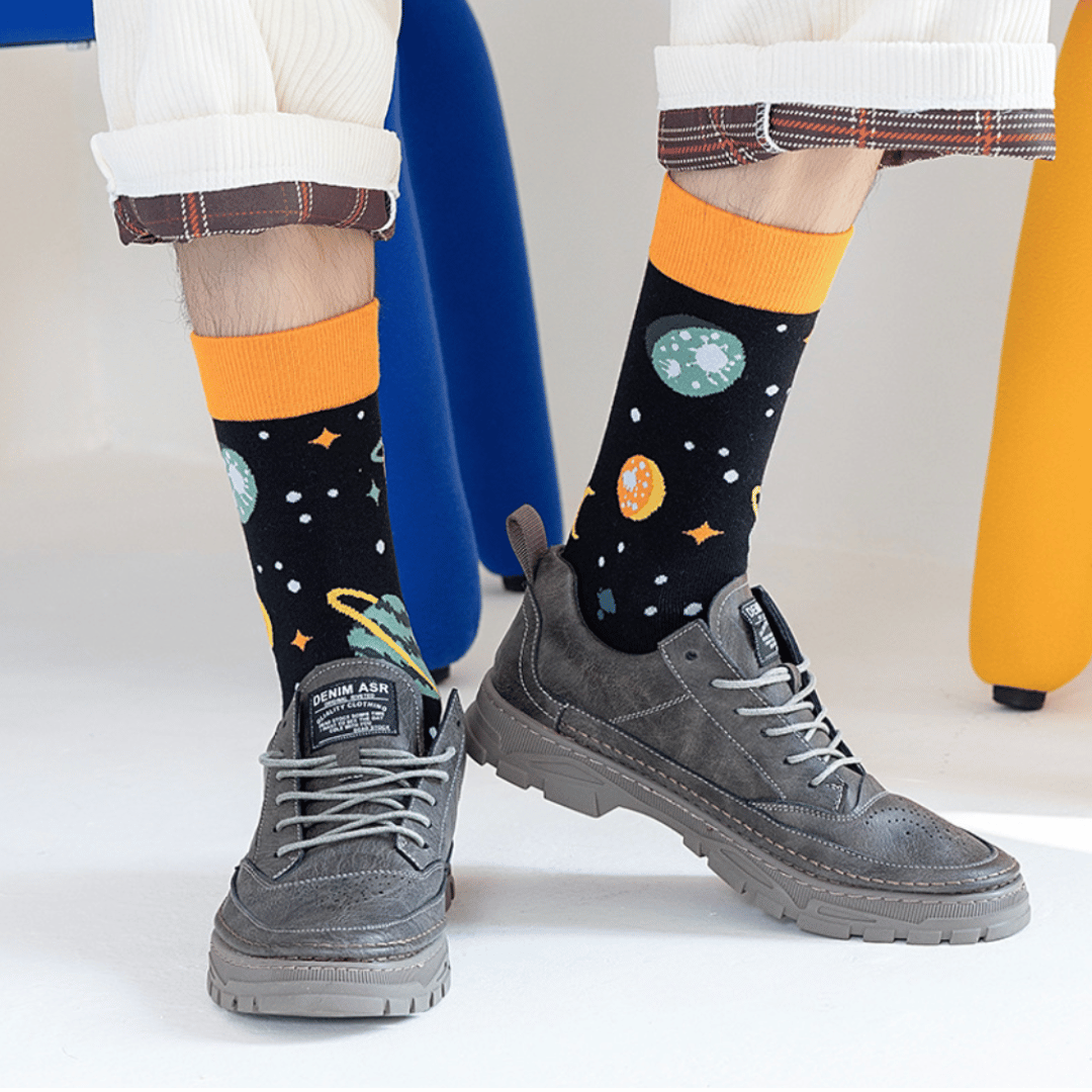 Men's and women's socks adorned with colorful graphics of various planets, stars, and cosmic elements, set against a deep space background